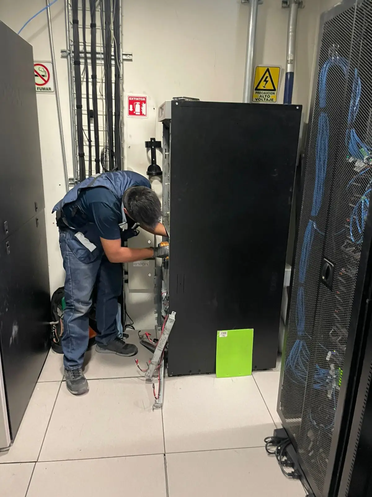 Técnico de JM Energy Solutions realizando mantenimiento correctivo a un UPS en cuarto de servidores.